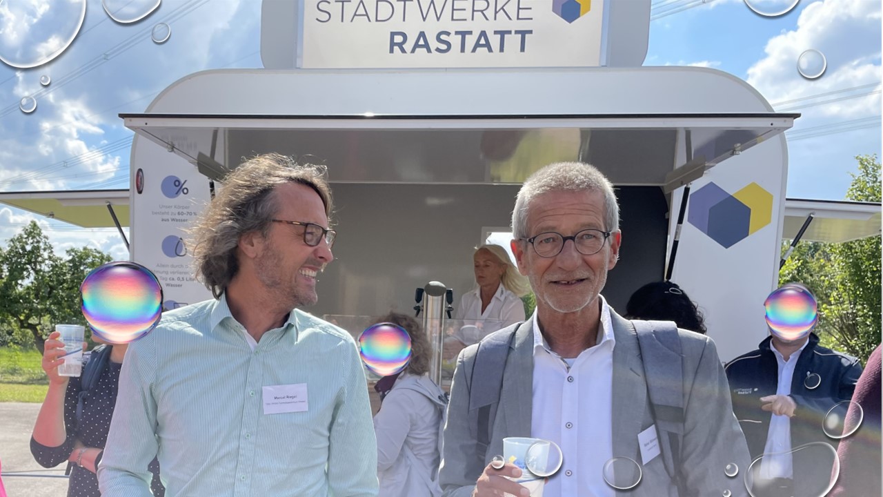 2 Männer trinken Wasser und lachen dabei